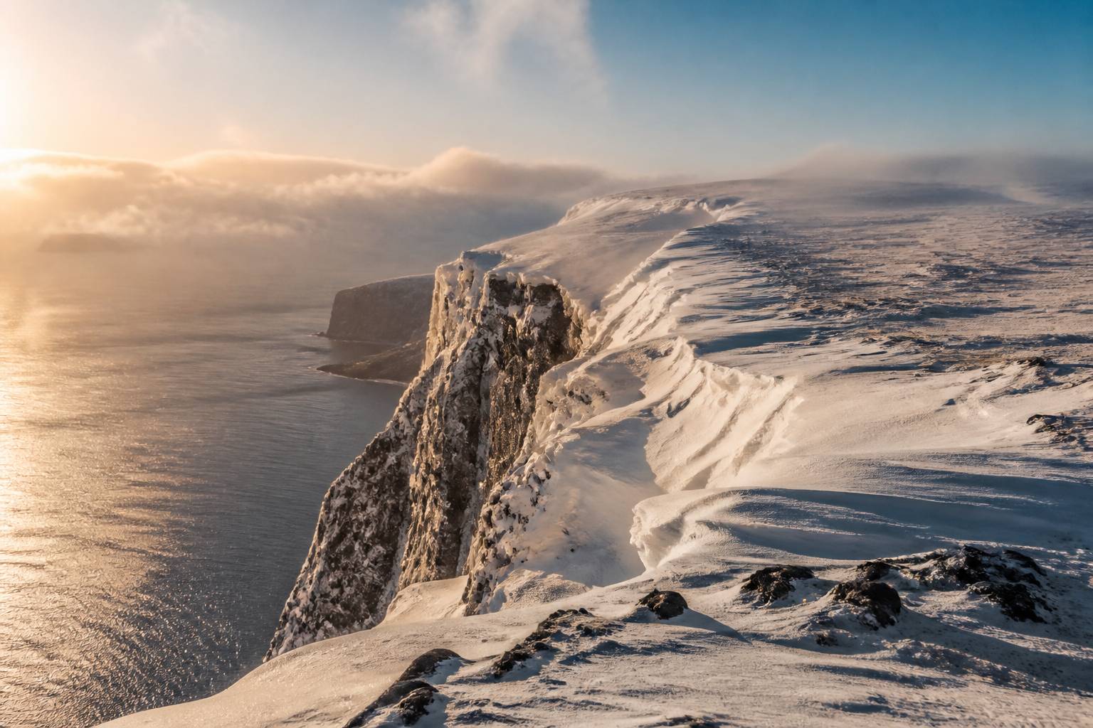 Plateau du Cap Nord couvert de neige surplombant la mer